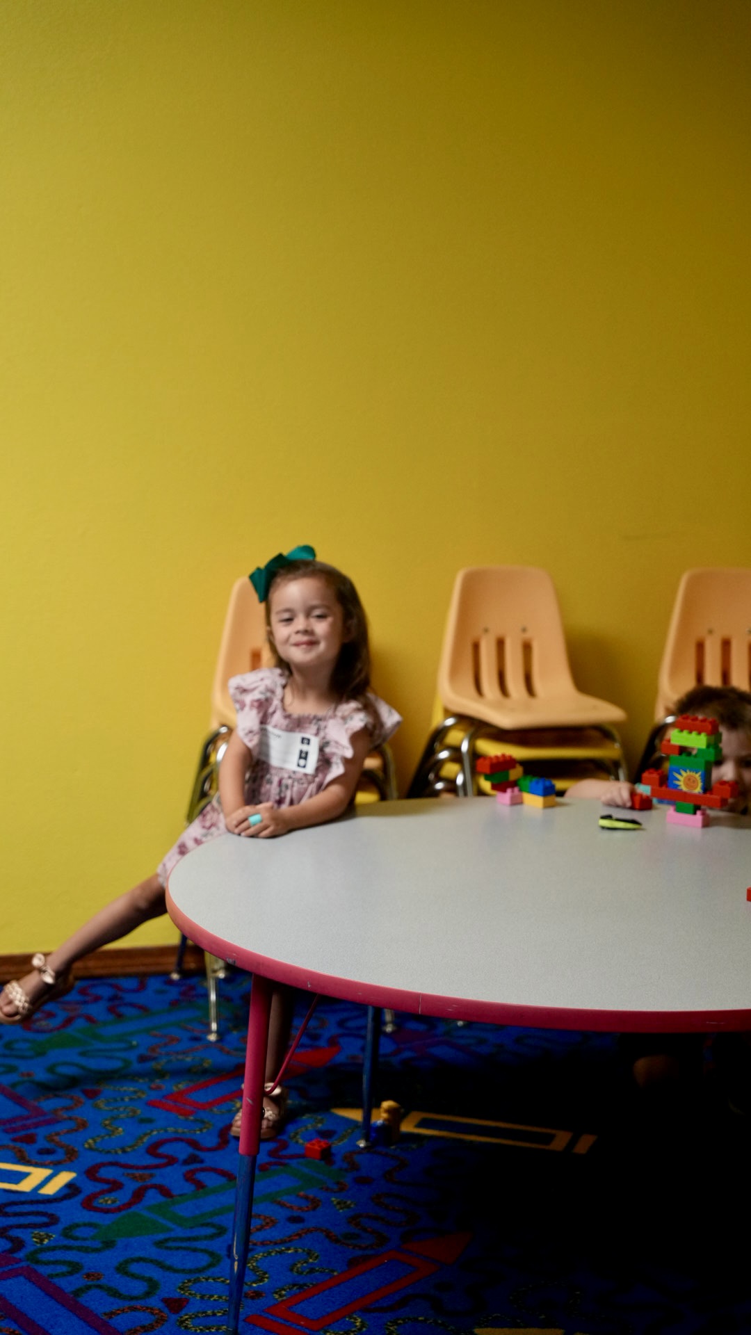 A young girl smiling at the kids classroom table