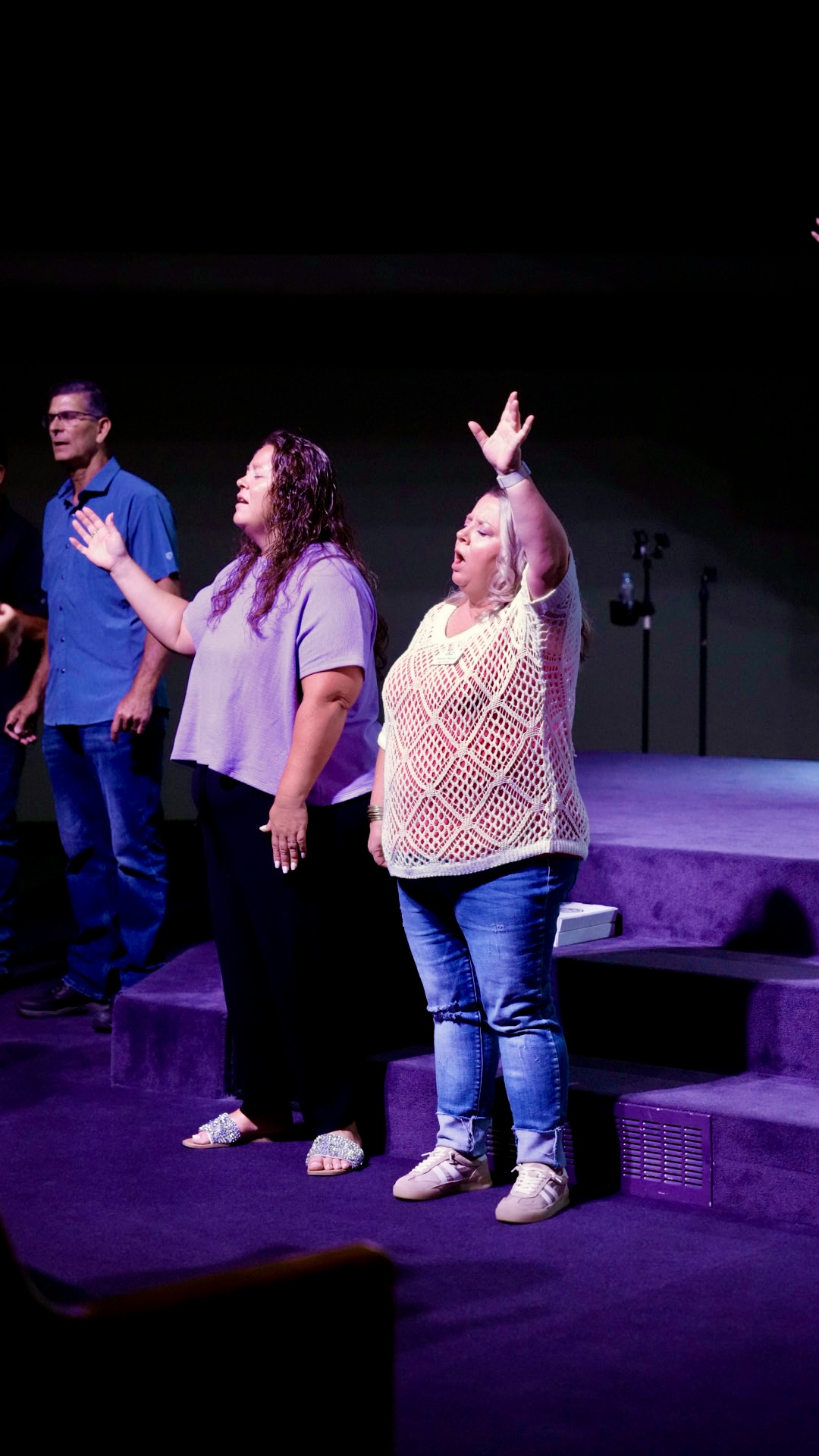 Women worshipping with hands raised near the stage