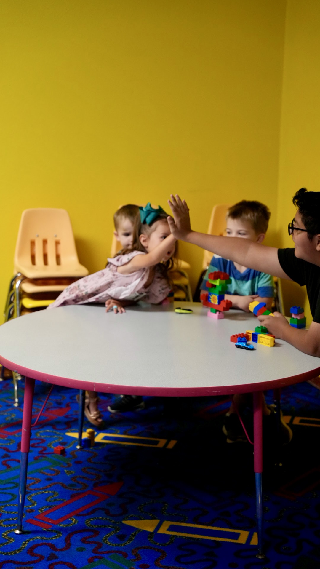 A kids volunteer high-fiving a child at the table