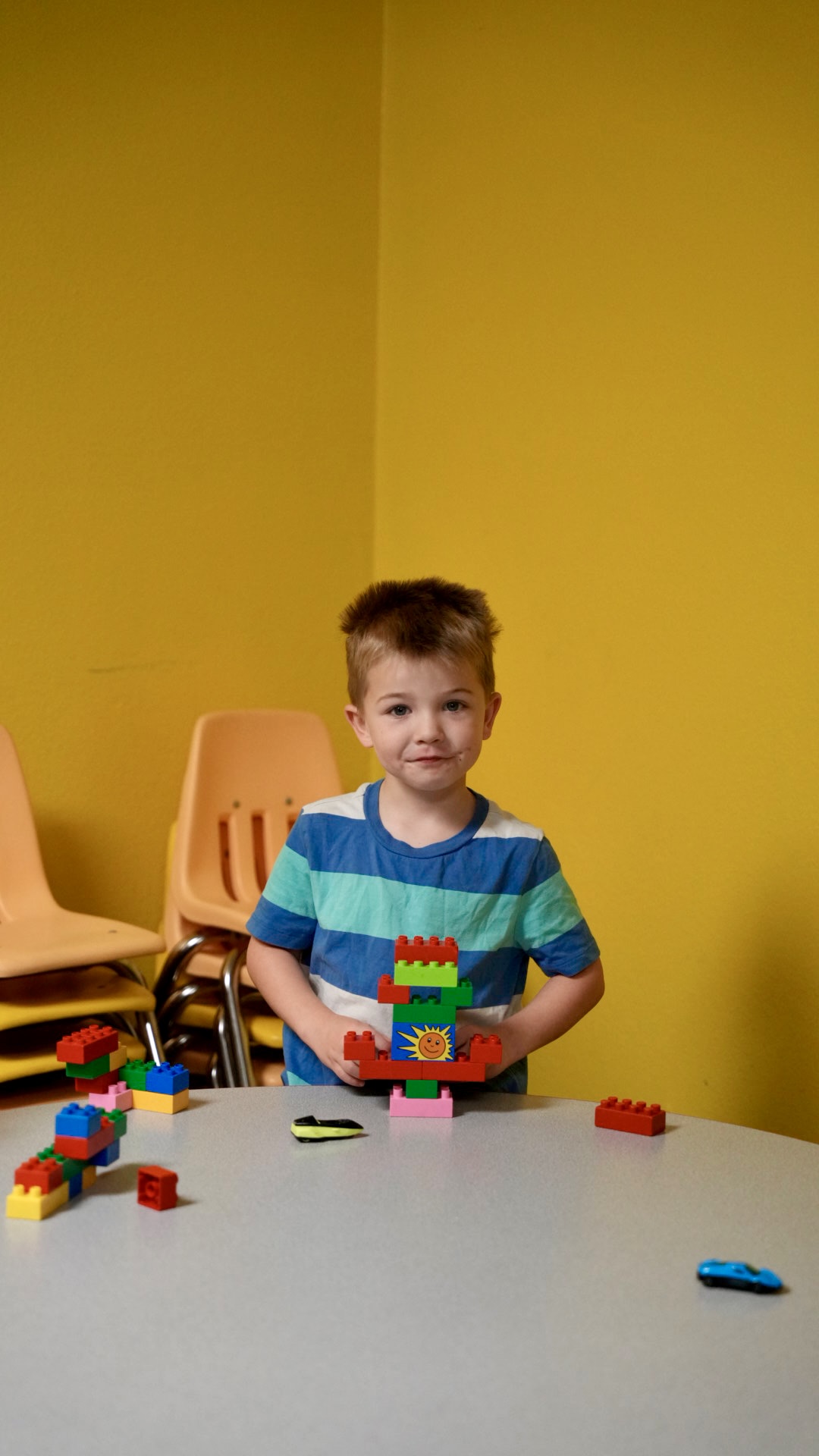 A boy showing off a block tower he built in kids class