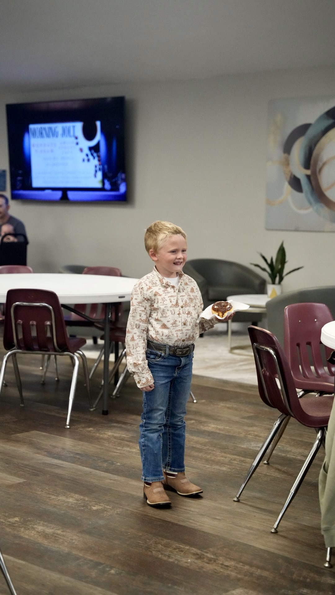 A young boy holding a donut in the fellowship hall
