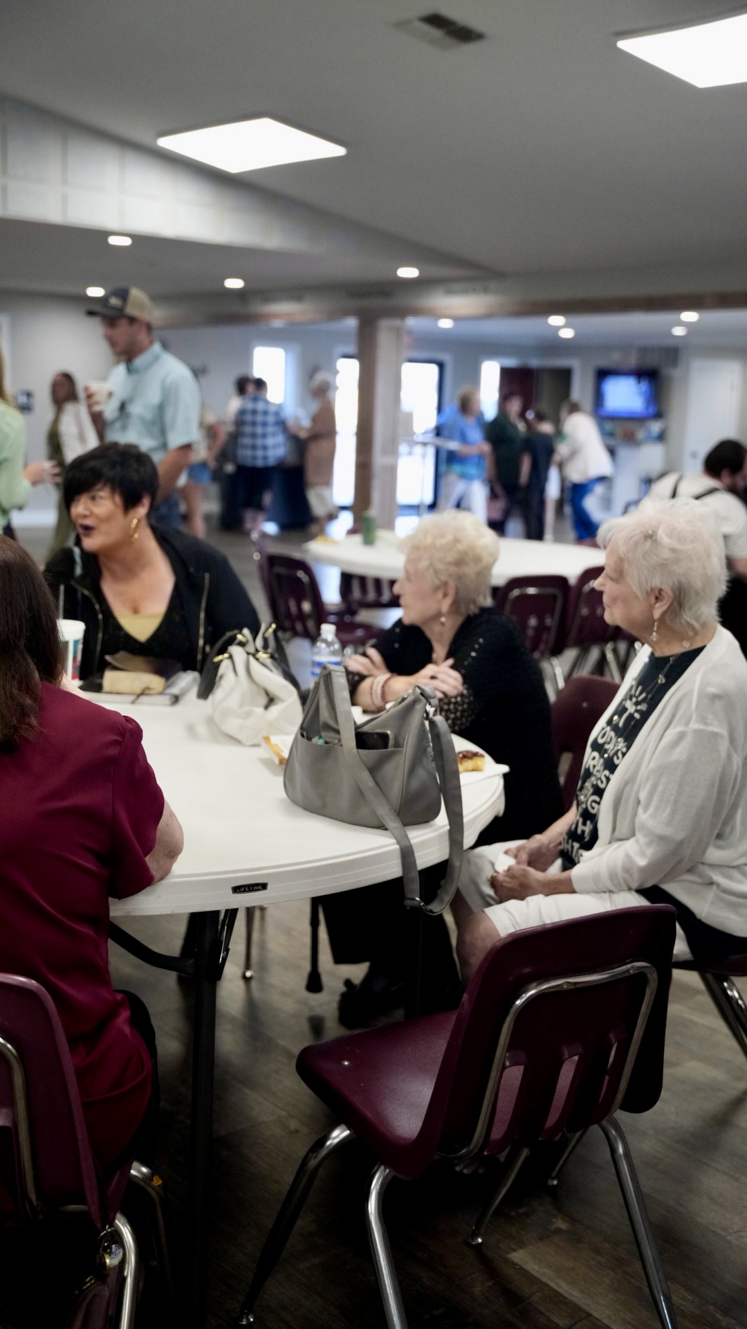 Church members visiting around tables in the fellowship hall